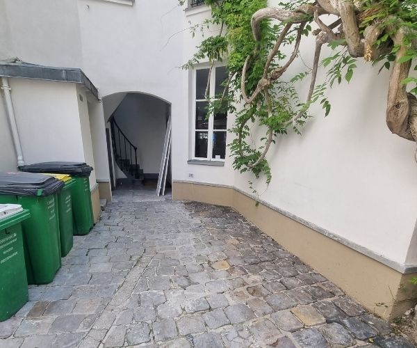 Cour intérieure pavée avec accès d’immeuble et plantes grimpantes à Paris