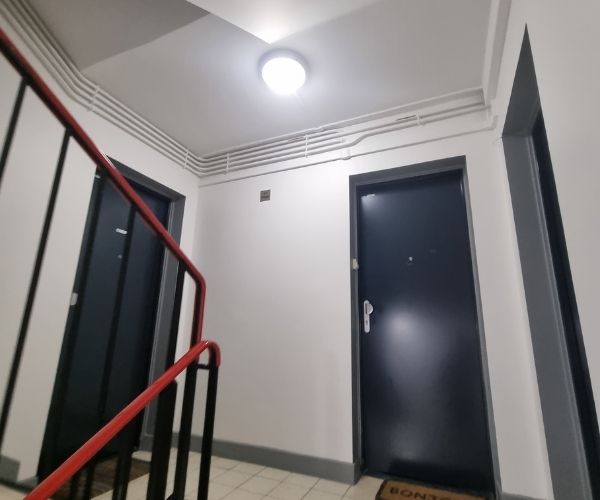 Palier d’immeuble rénové avec peinture blanche et éclairage moderne