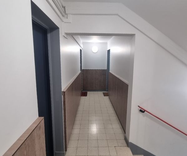 Couloir de parties communes rénové avec soubassement bois et murs peints